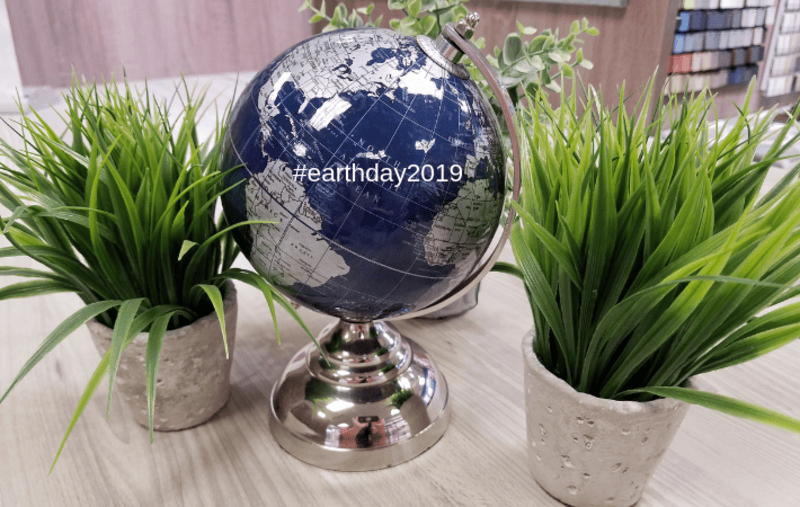 picture of a globe in between two fake plants on a table